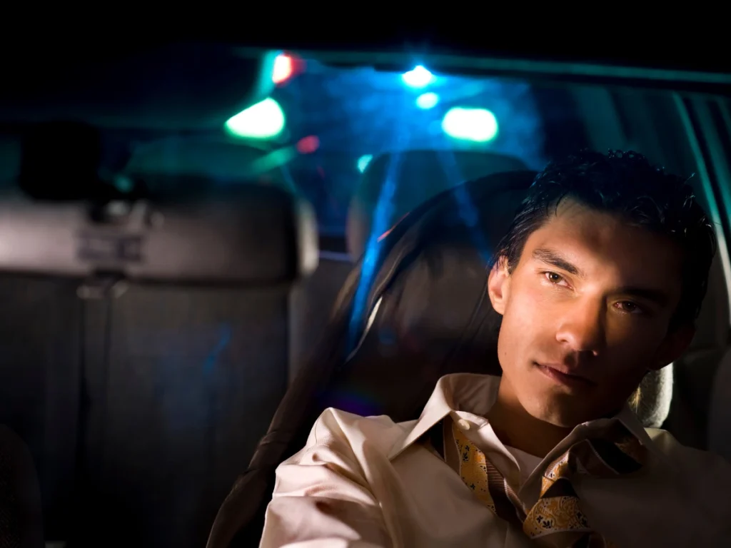 A man sitting in his car, appearing overwhelmed and anxious, illustrating the stress and emotional burden of coping with a DUI charge.